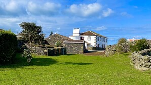 Una casa rural con un muro de piedra y un patio cubierto de césped.