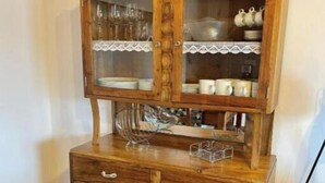 Un mueble de madera con puertas de cristal, cajones y una repisa con platos y tazas.