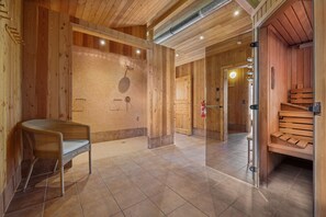 Un interior de madera con zona de ducha, una silla de mimbre y una sauna.