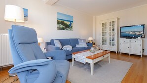 A living room with a blue sofa, a coffee table, and a TV on a cabinet.