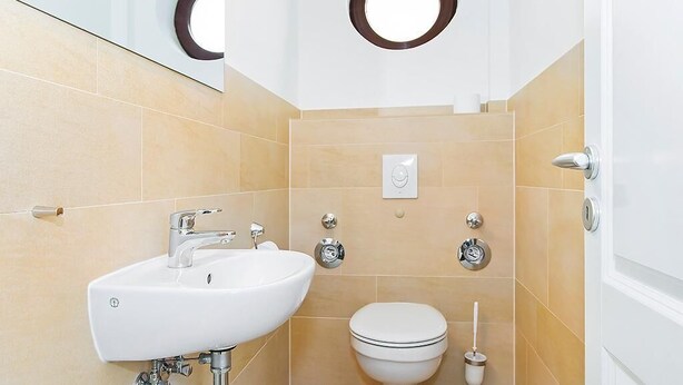 Un bagno con lavandino bianco, water e specchio con oblò circolare.