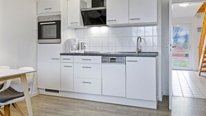 A modern kitchen with white cabinetry, a built-in oven, a dishwasher, and a stainless steel range hood.