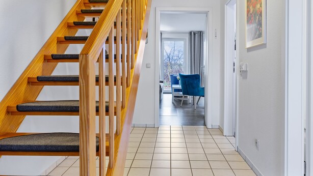A staircase with wooden railings and carpeted steps leading to a room with a view of the outdoors.