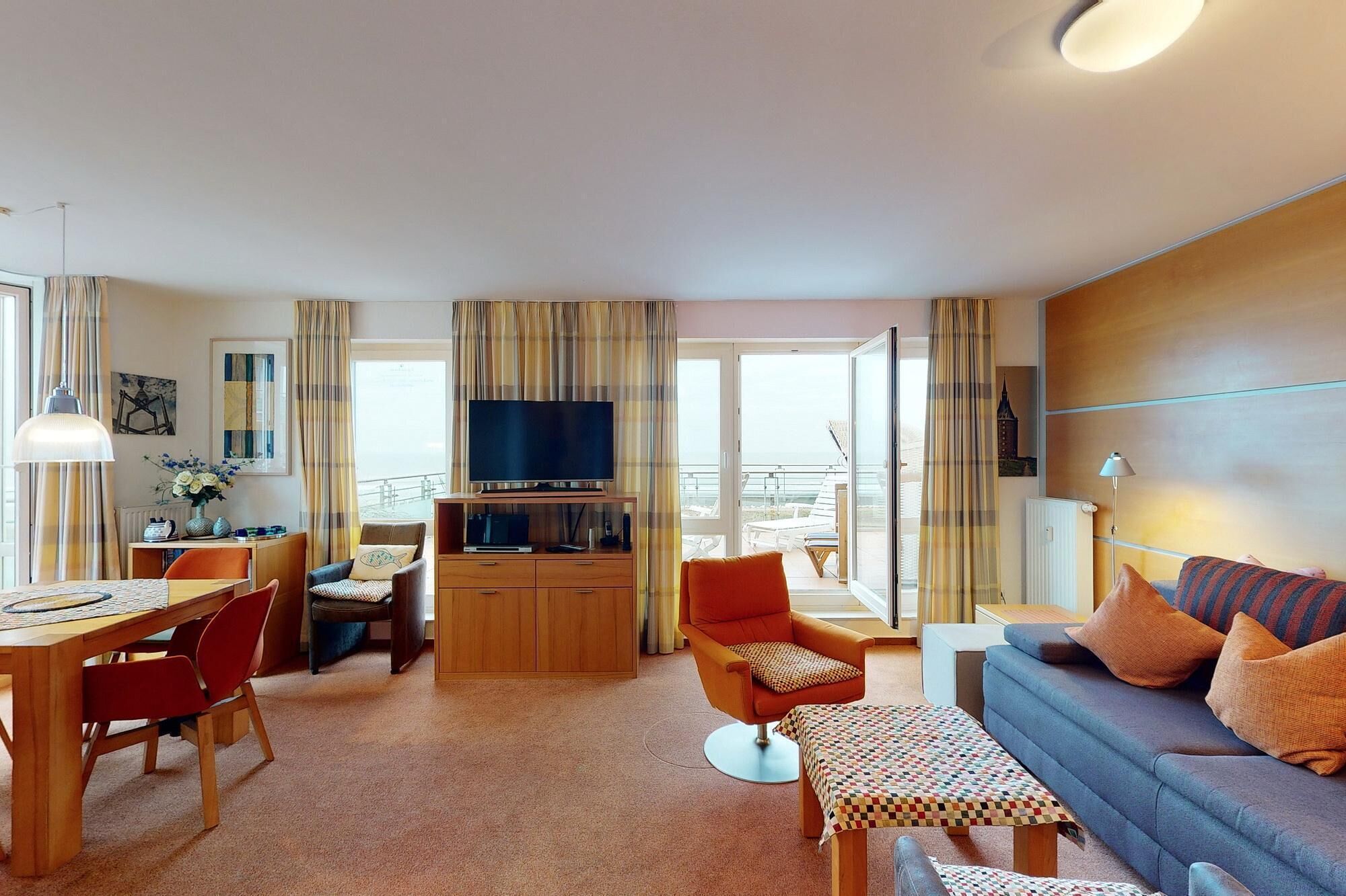 Een moderne woonkamer met een bank, een televisie, een eettafel en een balkon met uitzicht.