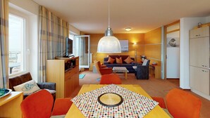 A hotel room with a dining area, a sofa set, a television, and a wardrobe.