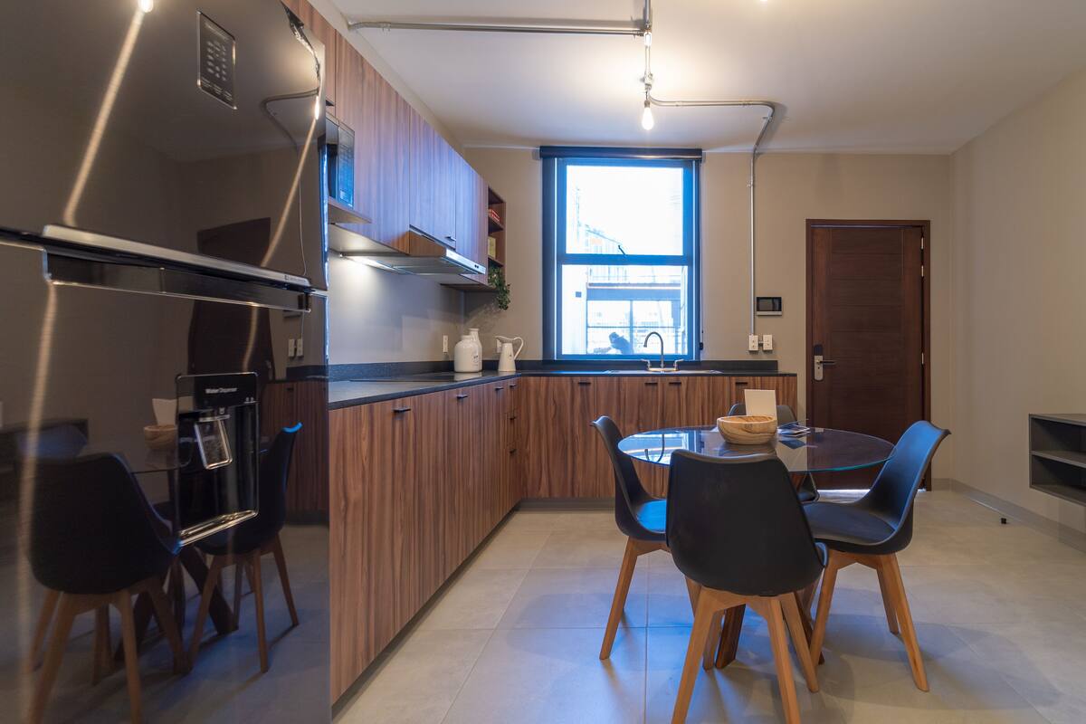 Una cocina moderna con una isla central, sillas negras y una mesa de comedor.