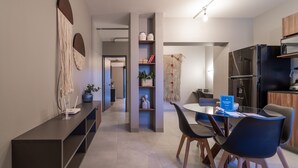 Una cocina moderna con refrigerador, microondas y estufa integrados. Hay un comedor con una mesa redonda y sillas.