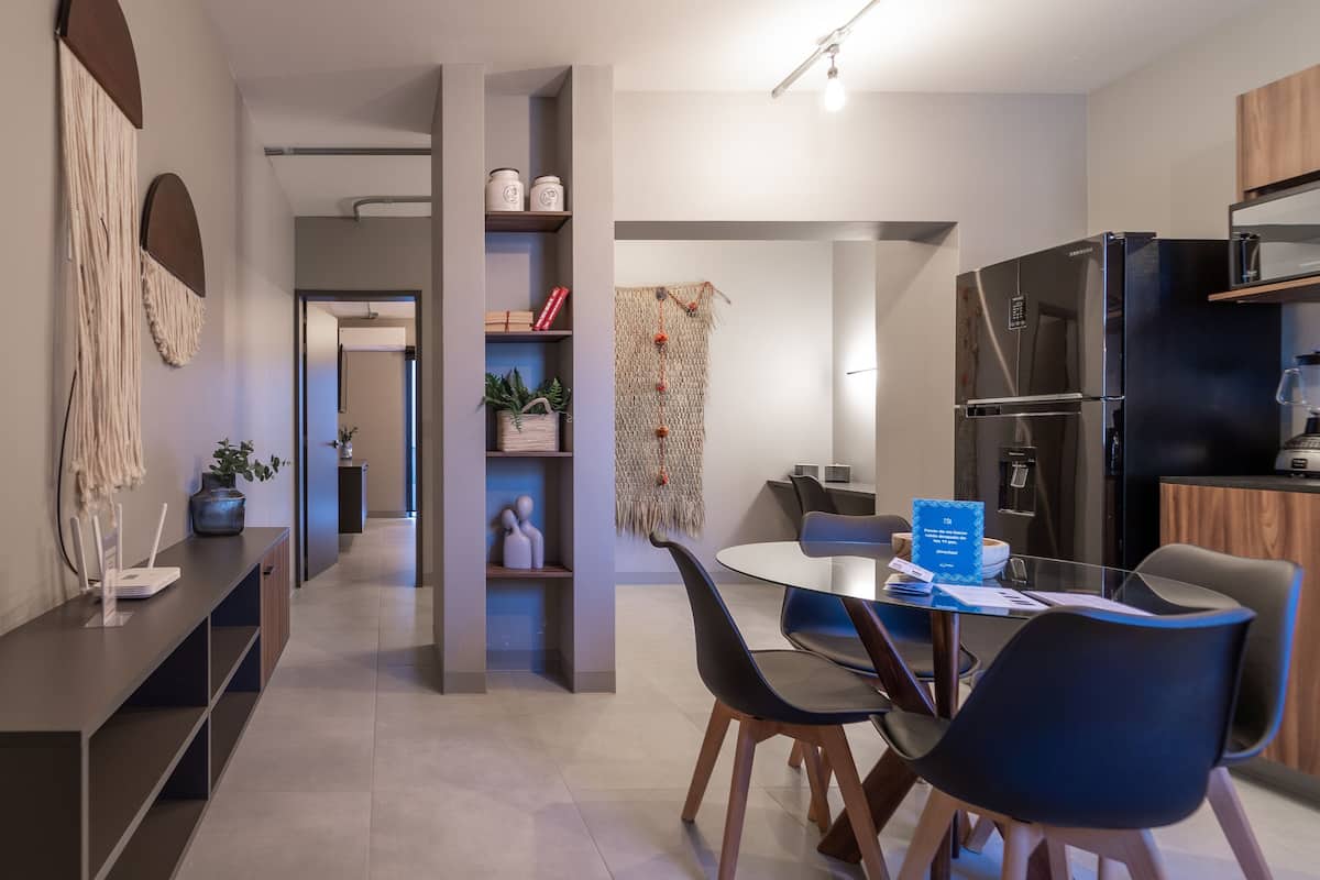Una cocina moderna con refrigerador, microondas y estufa integrados. Hay un comedor con una mesa redonda y sillas.