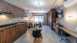 Una cocina moderna con armarios de madera, una isla central y un comedor con mesa redonda y sillas.