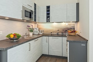 A modern kitchen with a built-in microwave, a coffee maker, and a fruit bowl.