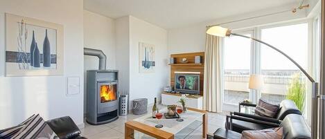 Ein modernes Wohnzimmer mit Kamin, Fernseher und Balkon mit Aussicht.
