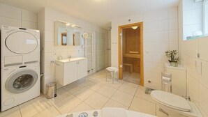 Un baño moderno con lavadora, lavamanos, espejo e inodoro.