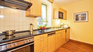 A kitchen with wooden cabinets, a stainless steel stove, a sink, and a window with a view of greenery.