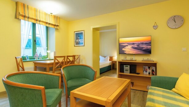 A room with a bed, a TV, a desk, and two chairs.