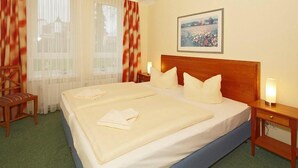 A neatly made double bed with pillows, a wooden headboard, and a bedside table with a lamp.