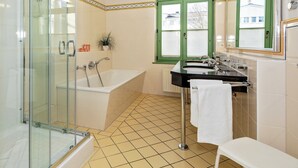 A bathroom with a glass-enclosed shower, a bathtub, a sink with a mirror, and a window with green frames. - 4-zimmer Ferienwohnung mit Wintergarten und Terrasse in Toplage an der Promenade (Heringsdorf)