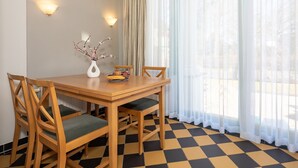 A dining area with a checkered floor, wooden chairs, a table, and a vase with branches. - 4-zimmer Ferienwohnung mit Wintergarten und Terrasse in Toplage an der Promenade (Heringsdorf)