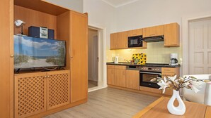 A compact kitchen with wooden cabinets, a microwave, and a coffee maker. - 4-zimmer Ferienwohnung mit Wintergarten und Terrasse in Toplage an der Promenade (Heringsdorf)