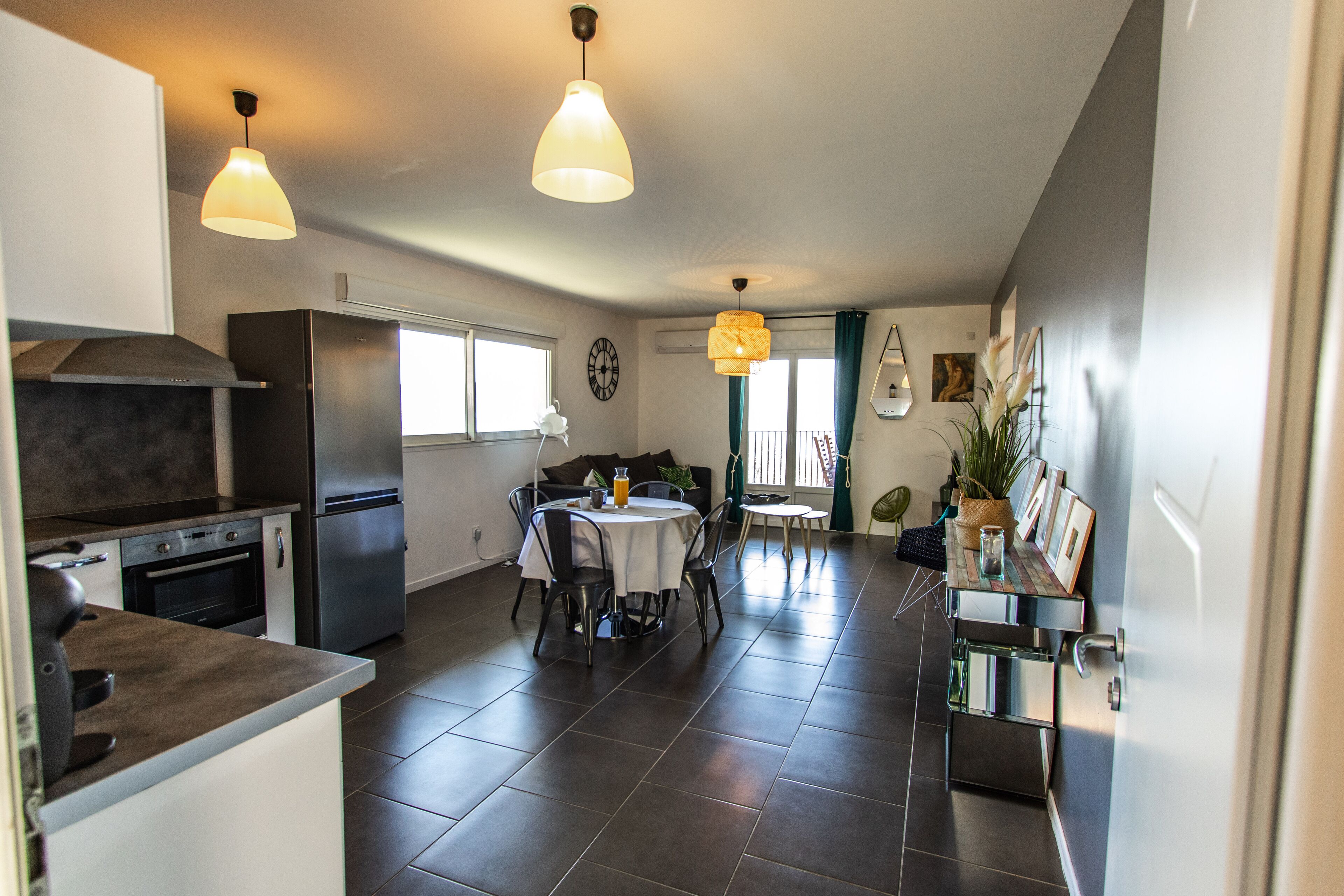 A modern kitchen with a dining area, featuring a large island, stainless steel appliances, and pendant lighting.