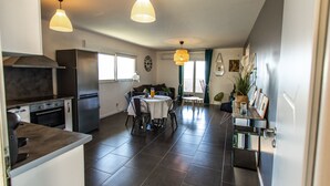 A modern kitchen with a dining area, featuring a large island, stainless steel appliances, and pendant lighting. - New accommodation, summer kitchen, terrace, garden (Olmeto)