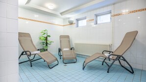 Una habitación con tres sillones reclinables, una planta en maceta y un ventanal.