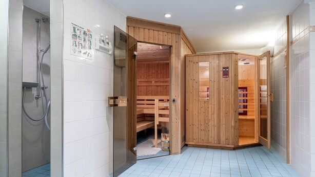Un baño moderno con ducha, sauna de madera y suelo de baldosas.