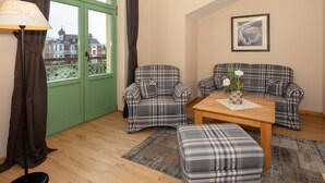 A living room with plaid furniture, a wooden coffee table, and a view through a green door.