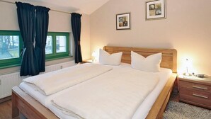A neatly made bed with white linens, a wooden headboard, and two bedside tables with lamps.