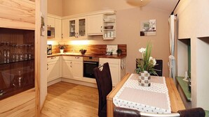 A compact kitchen with wooden cabinets, a dining table with chairs, and a small countertop with a microwave and coffee maker.