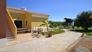 A yellow building with a tiled roof, outdoor seating, and a staircase leading to an entrance. - Kine Villa, Armação de Pêra, Algarve (Armação de Pêra)