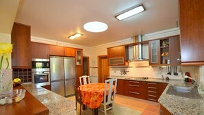 A modern kitchen with wooden cabinets, stainless steel appliances, and a granite countertop. - Kine Villa, Armação de Pêra, Algarve (Armação de Pêra)