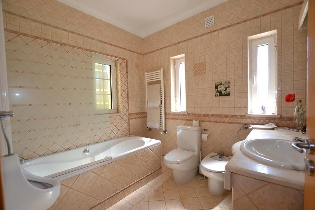 Une salle de bain avec une baignoire, deux toilettes, un lavabo et une fenêtre.