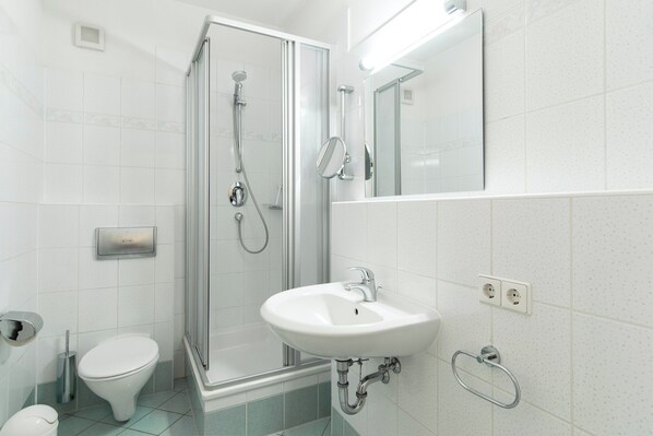 A modern bathroom with a glass-enclosed shower, a white sink, and a toilet.