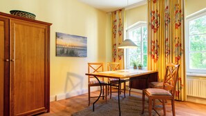 Un comedor con una mesa de madera, sillas, un armario y un cuadro en la pared.