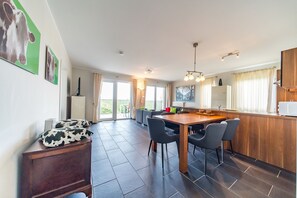 Une cuisine moderne avec une table à manger en bois, des chaises grises et un coin bar.