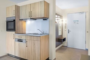 Eine moderne Küche mit Holzausstattung, einem eingebauten Ofen und einer Edelstahlspüle.
