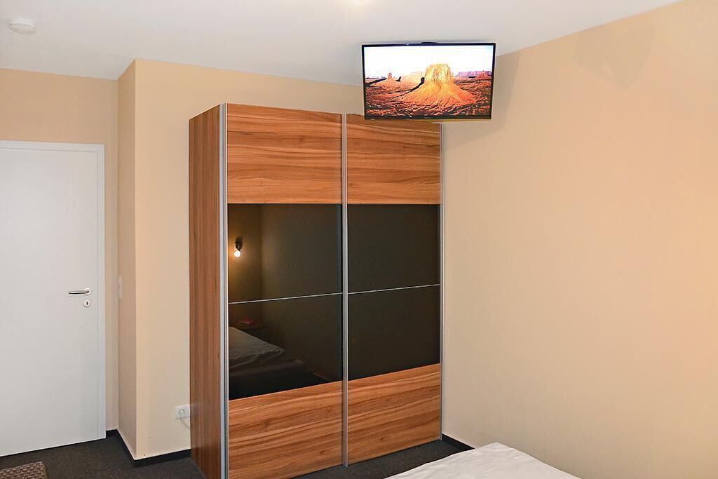 Quarto com guarda-roupa, televisão na parede e porta.