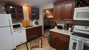 A kitchen with wooden cabinets, a microwave, a stove, and a dining table with woven placemats. - Serenity between the lakes and seashore (Westbrook)