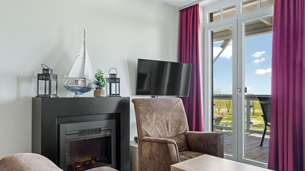 A living room with a fireplace, a television, and a view of the outdoors.
