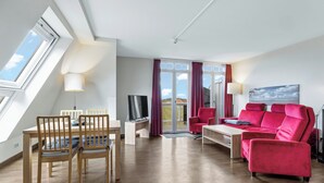 Una sala de estar moderna con una mesa de comedor de madera, un sofá rojo y un televisor.