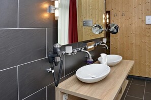 Ein modernes Badezimmer mit zwei Waschbecken, einem Föhn und einem Spiegel.