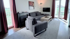 A modern living room with a sofa, a coffee table, a flat-screen TV, and a fireplace.