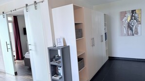 A modern hotel room with a sliding door, a grey bookshelf, and a large wardrobe.