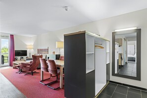 Ein Hotelzimmer mit Essbereich, einem Fernseher, einer Couch und einem Spiegel.