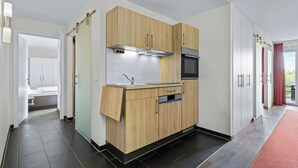A modern kitchen with wooden cabinets, a stainless steel range hood, and a built-in oven.