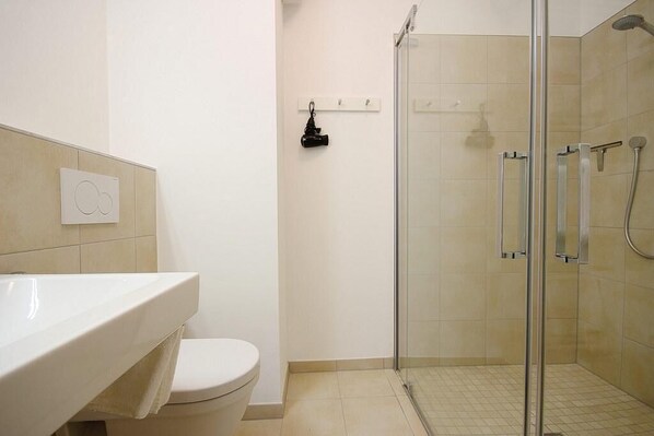 A bathroom with a white sink, toilet, and a glass-enclosed shower area.