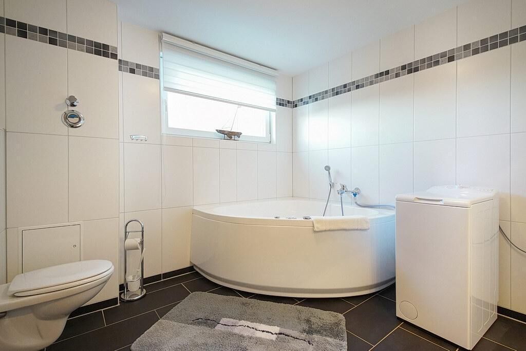 Un baño con inodoro, bañera y lavadora.
