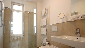 A modern bathroom with a glass shower enclosure, a white sink, and a mirror.