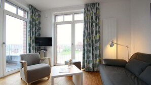 A modern living room with a sofa, armchair, and a TV on a stand.