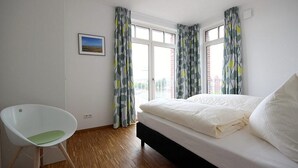A bedroom with a bed, a chair, and a window with curtains.